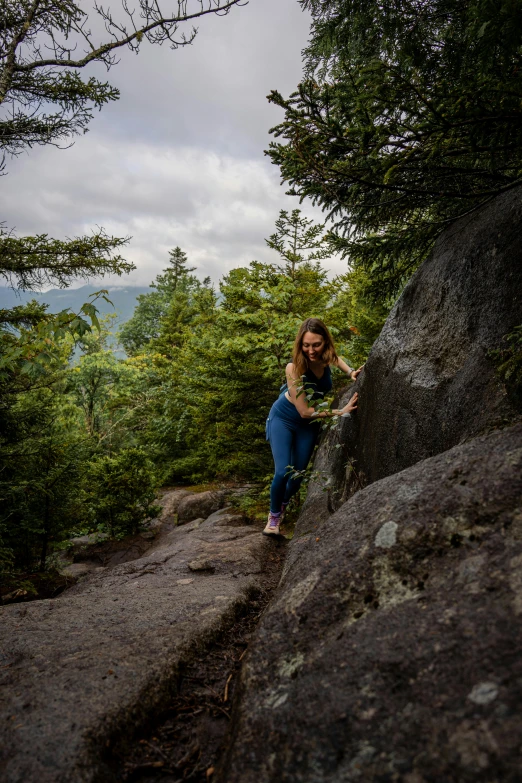 a woman climbs up on a rock in a scenic setting