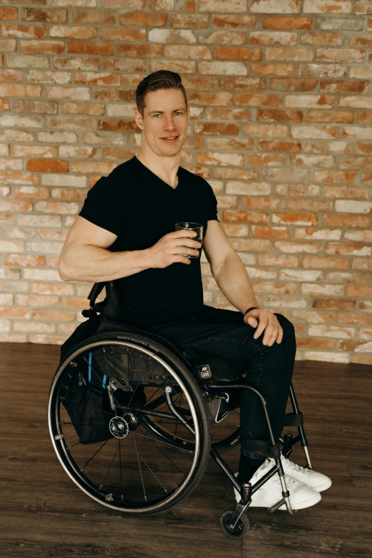 a man in a wheelchair holding a cup smiling