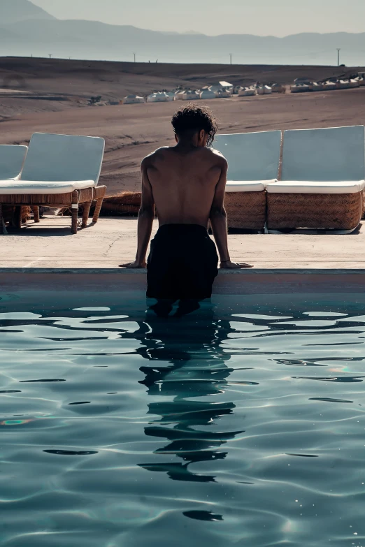 a man sitting on the edge of a swimming pool