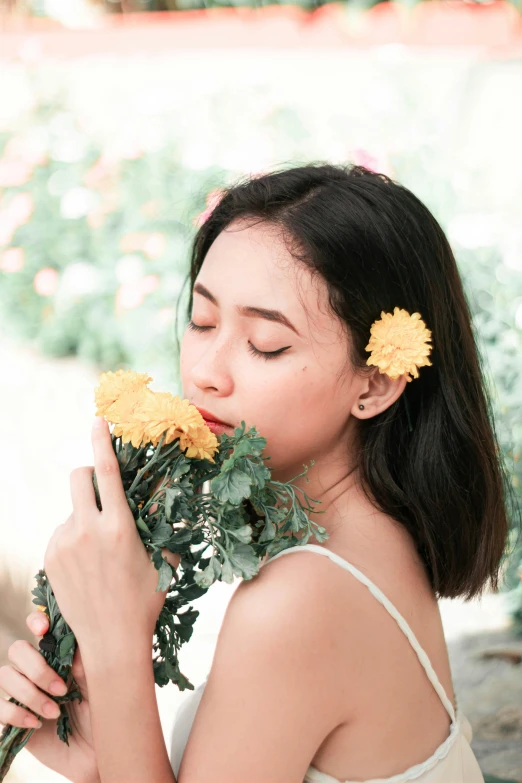 a young woman with two flowers on her hair smelling a flower