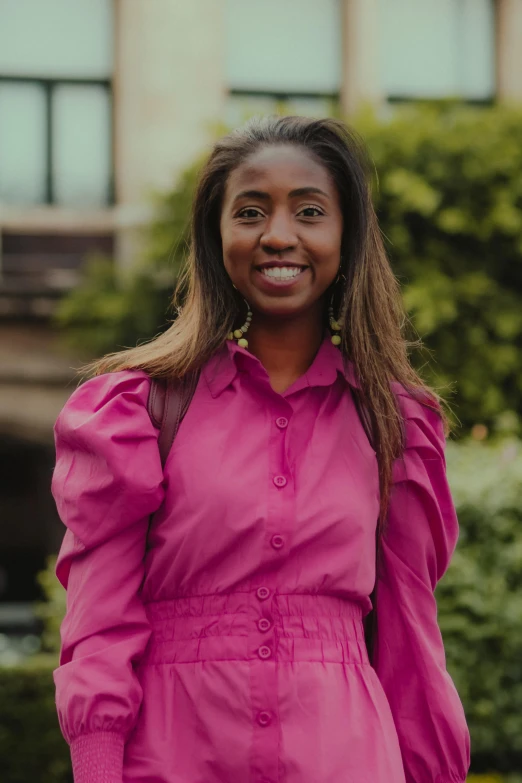 a woman in pink with black hair smiles for a po