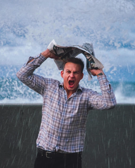 a man standing on the beach with an umbrella over his head