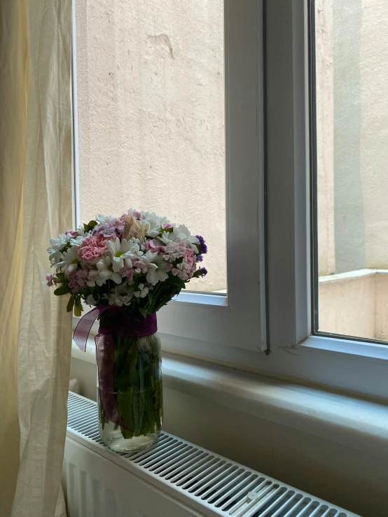 a vase of flowers by the window on a windowsill
