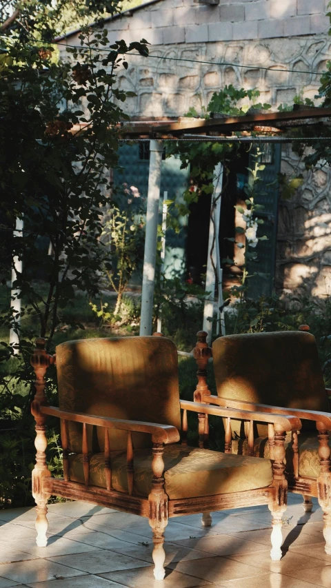 two antique seats and one table are sitting in front of a stone building