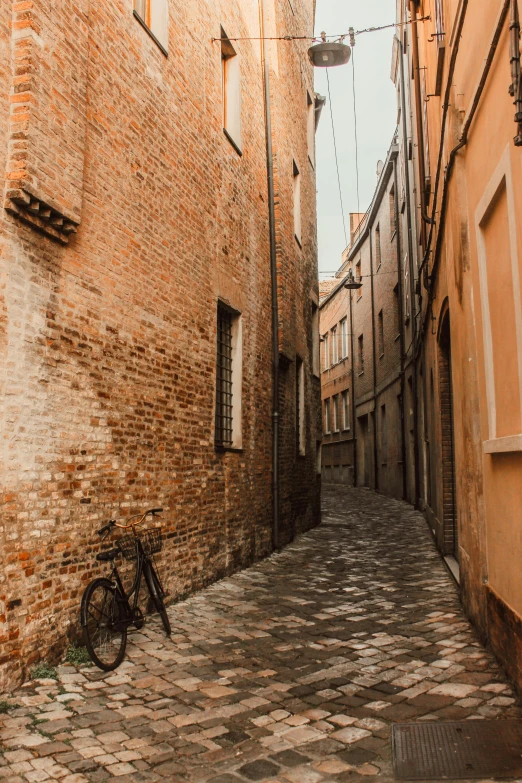 an empty cobblestone street with a bicycle leaning against the building