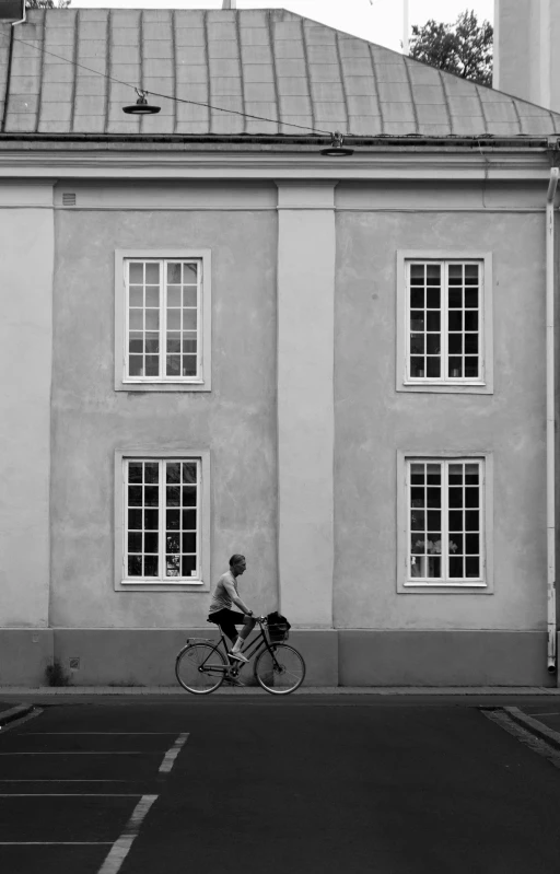 a woman riding a bike past a white building