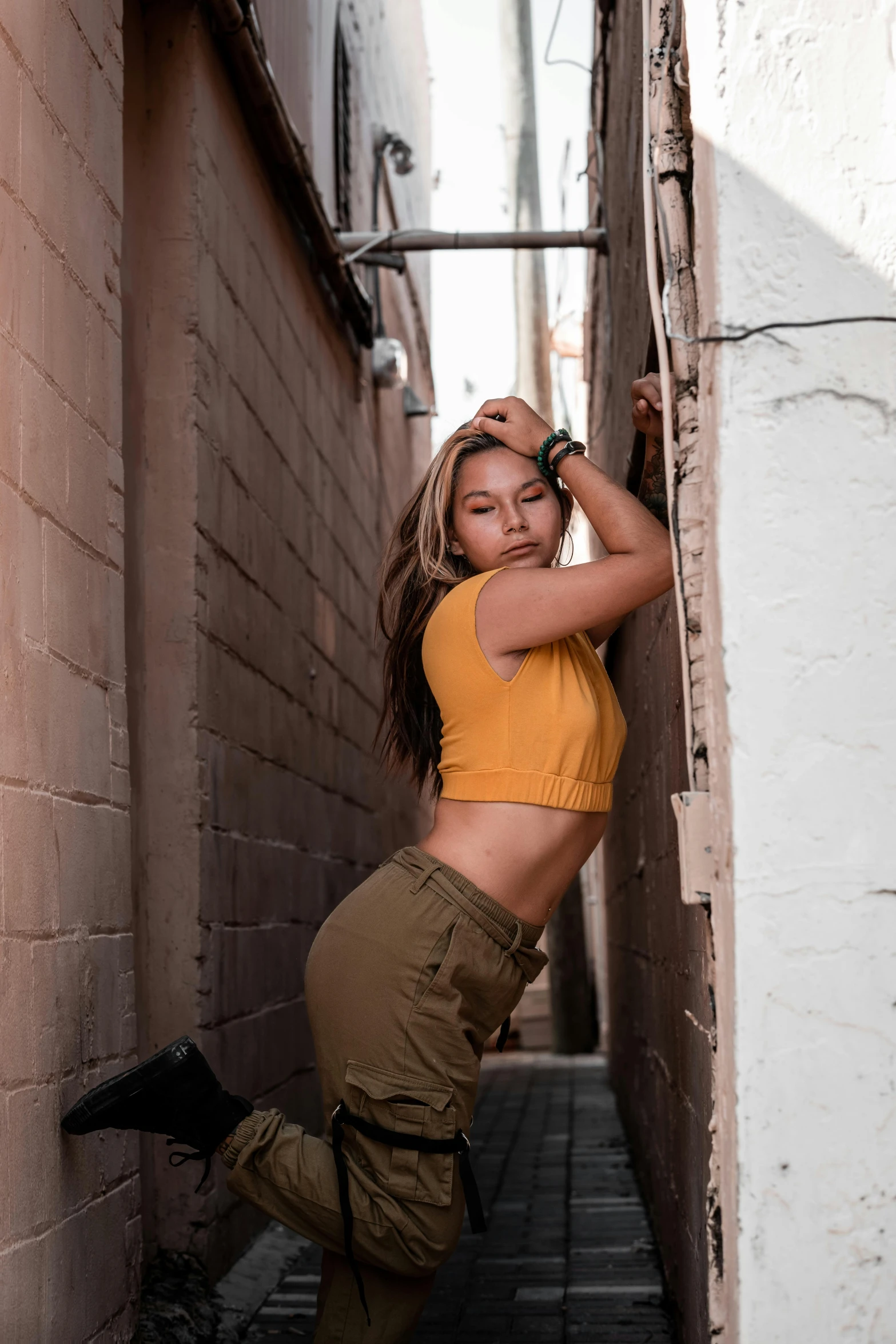 a woman in yellow shirt and pants leaning on wall