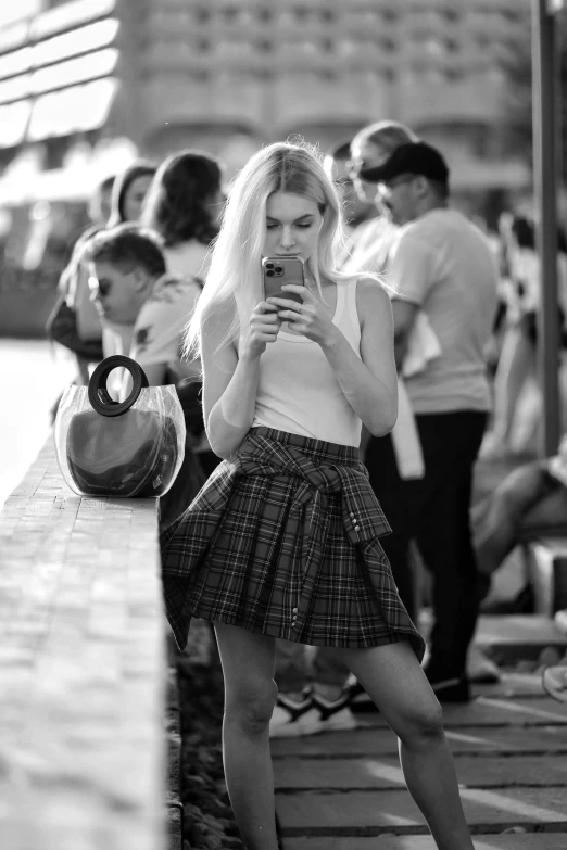 a young woman is standing outdoors and looking at her phone