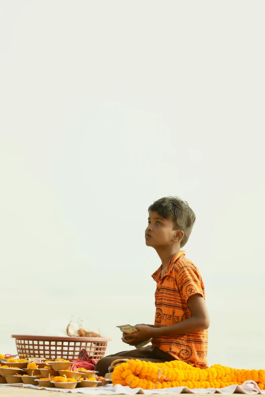 a young man sits on the ground holding a plate