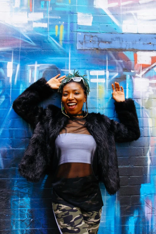 a woman is standing by a wall with graffiti