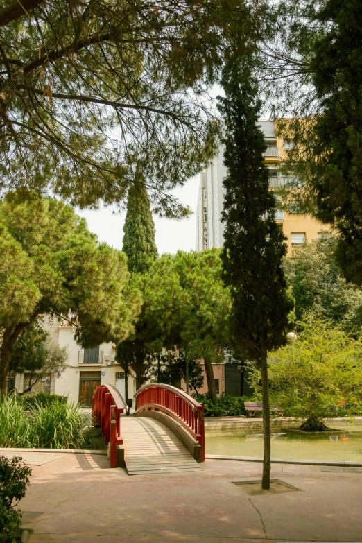 a red bridge is seen in a large park