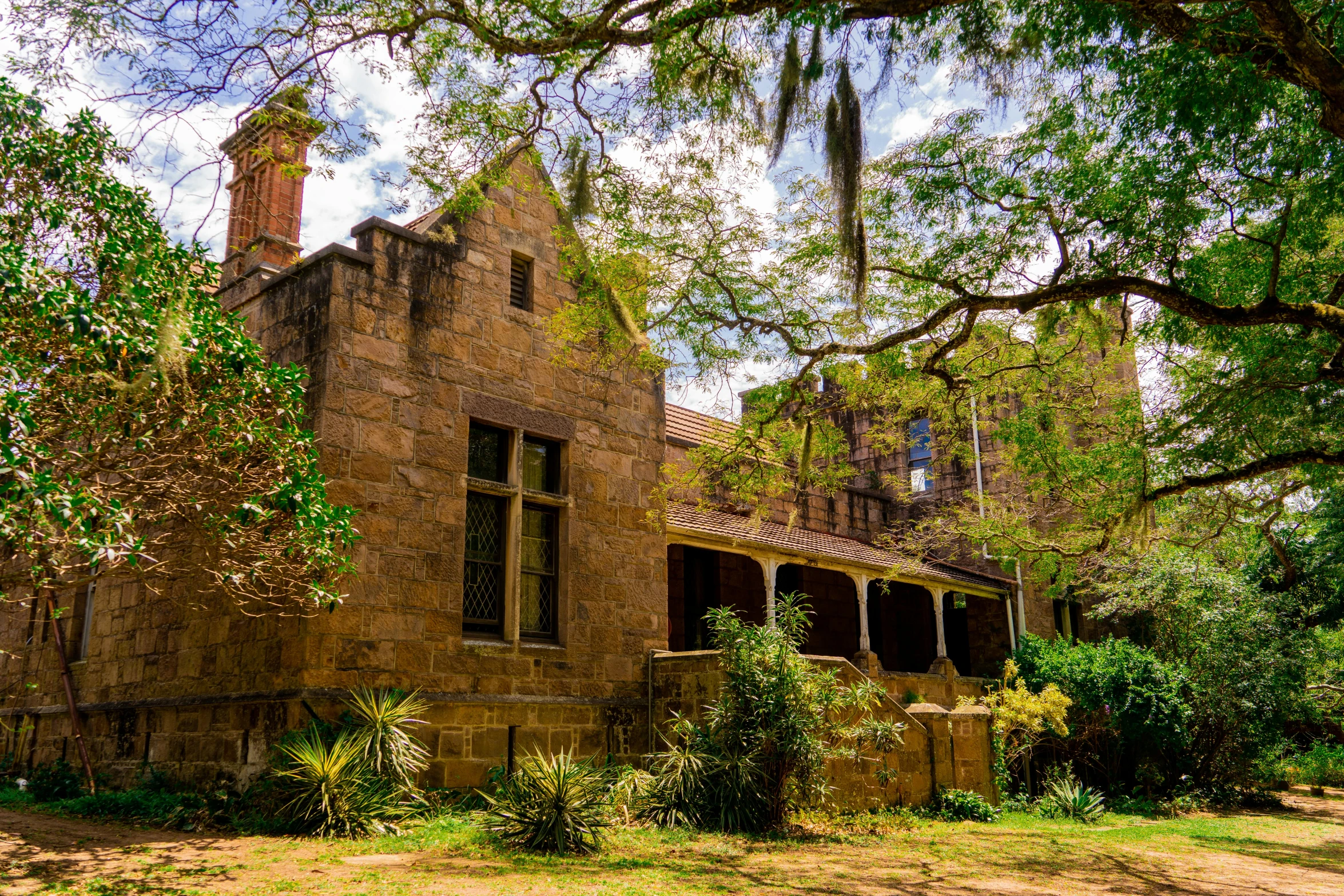 a brown brick house sitting next to green trees