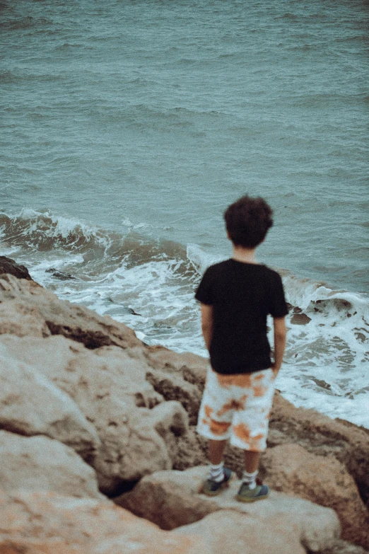 a  stands on rocks next to the ocean