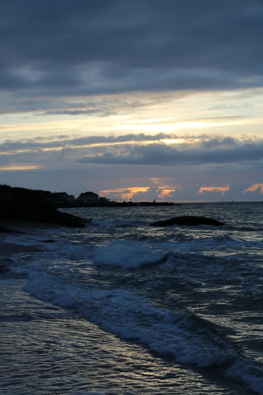 a person walking on a sandy beach under a cloudy sky