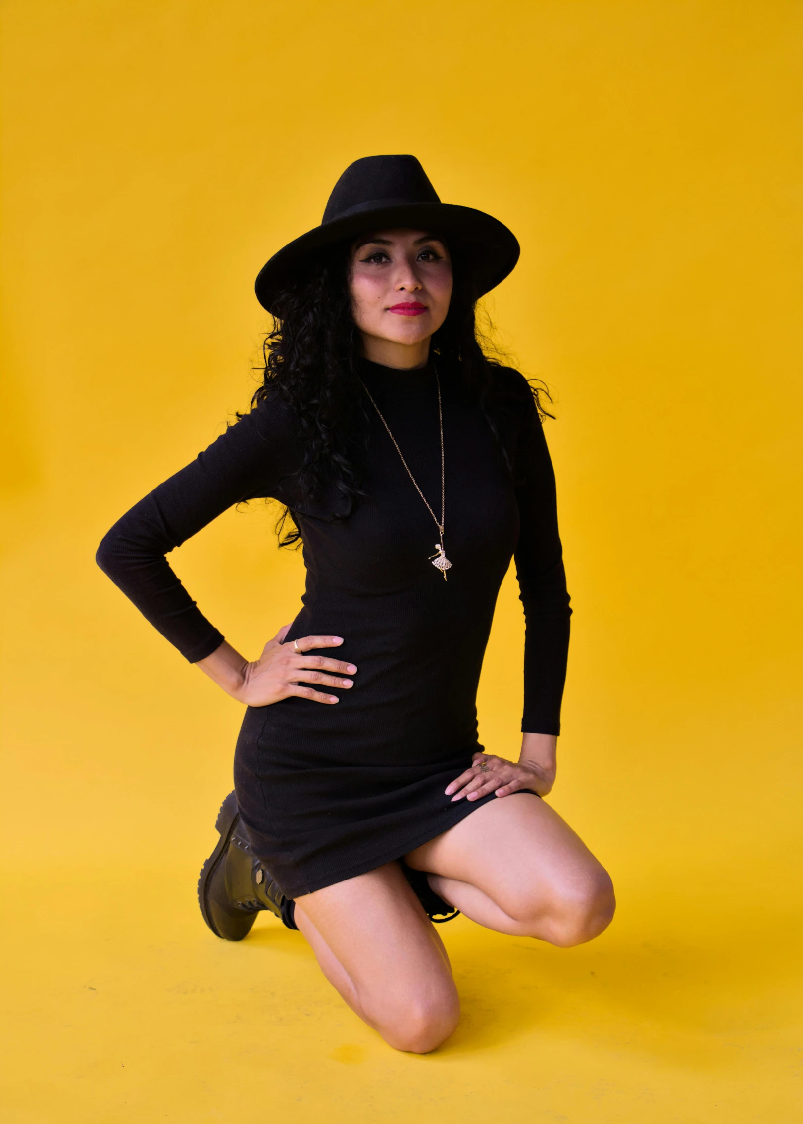 a young woman is posing wearing a black hat