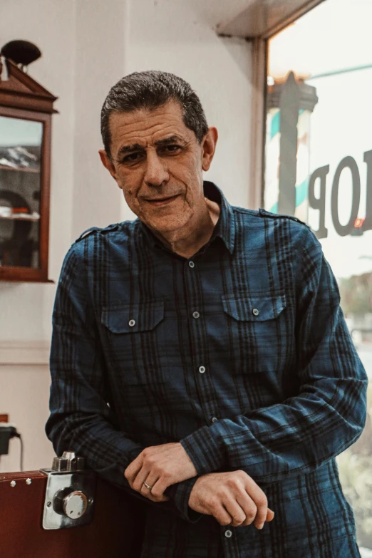 a man holding his own small camera by a stop sign