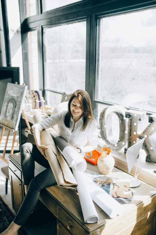 a woman sitting on top of a desk with an easel