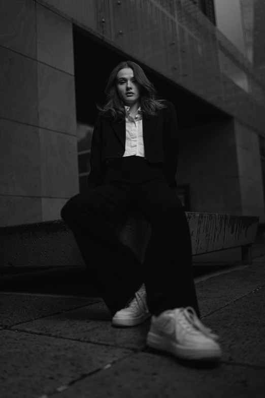 a black and white pograph of a woman sitting outside a building