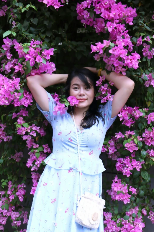 a young woman posing in front of pink flowers