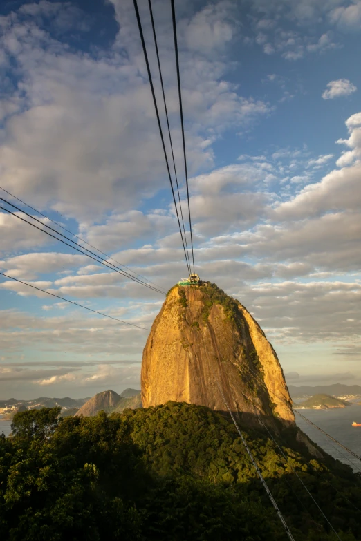 a power line sitting in front of a mountain under a cloudy blue sky