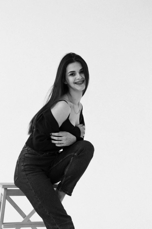 a beautiful young woman sitting on top of a chair smiling