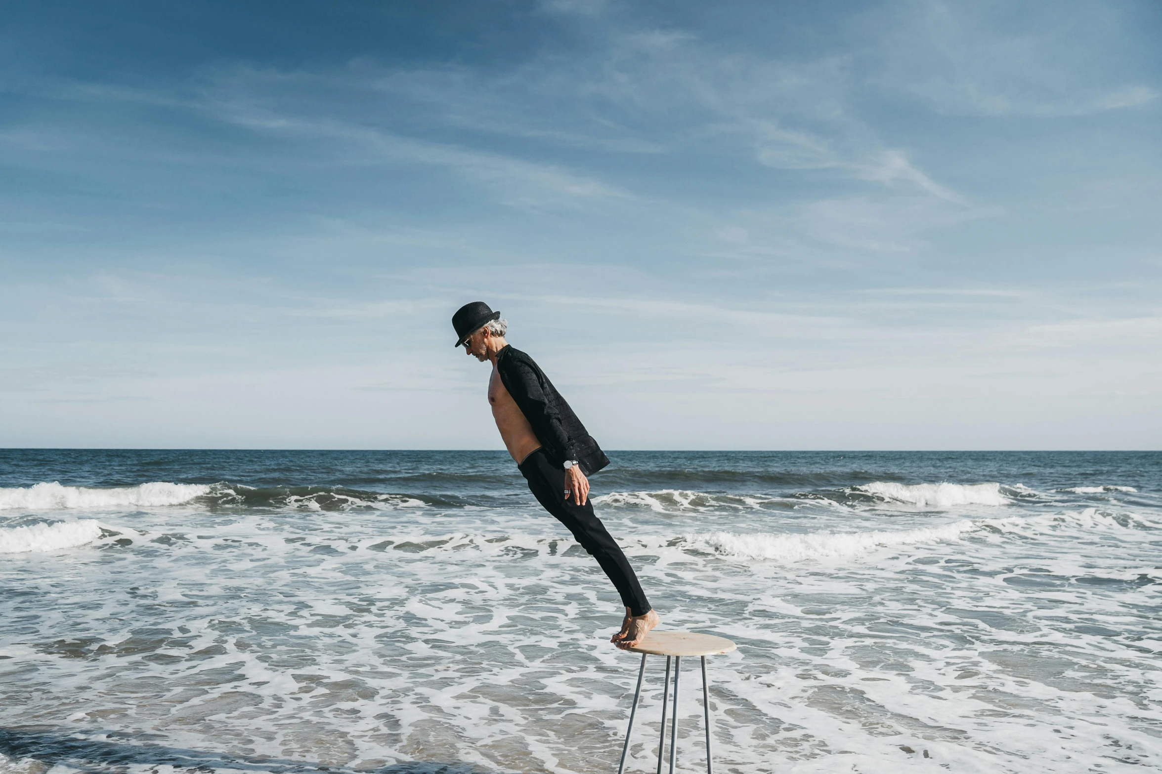 there is a man standing on a surf board on the beach