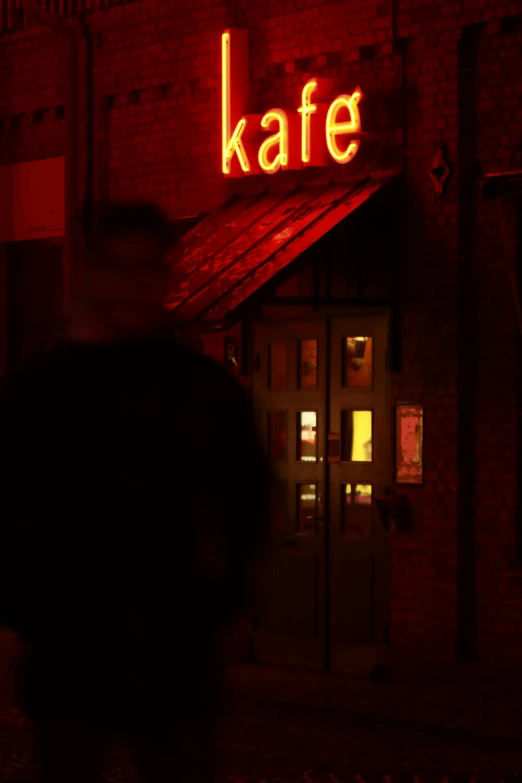 a man walking past a brick building at night