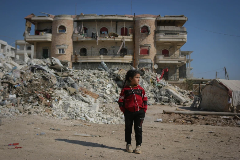 a young person stands in front of an abandoned building