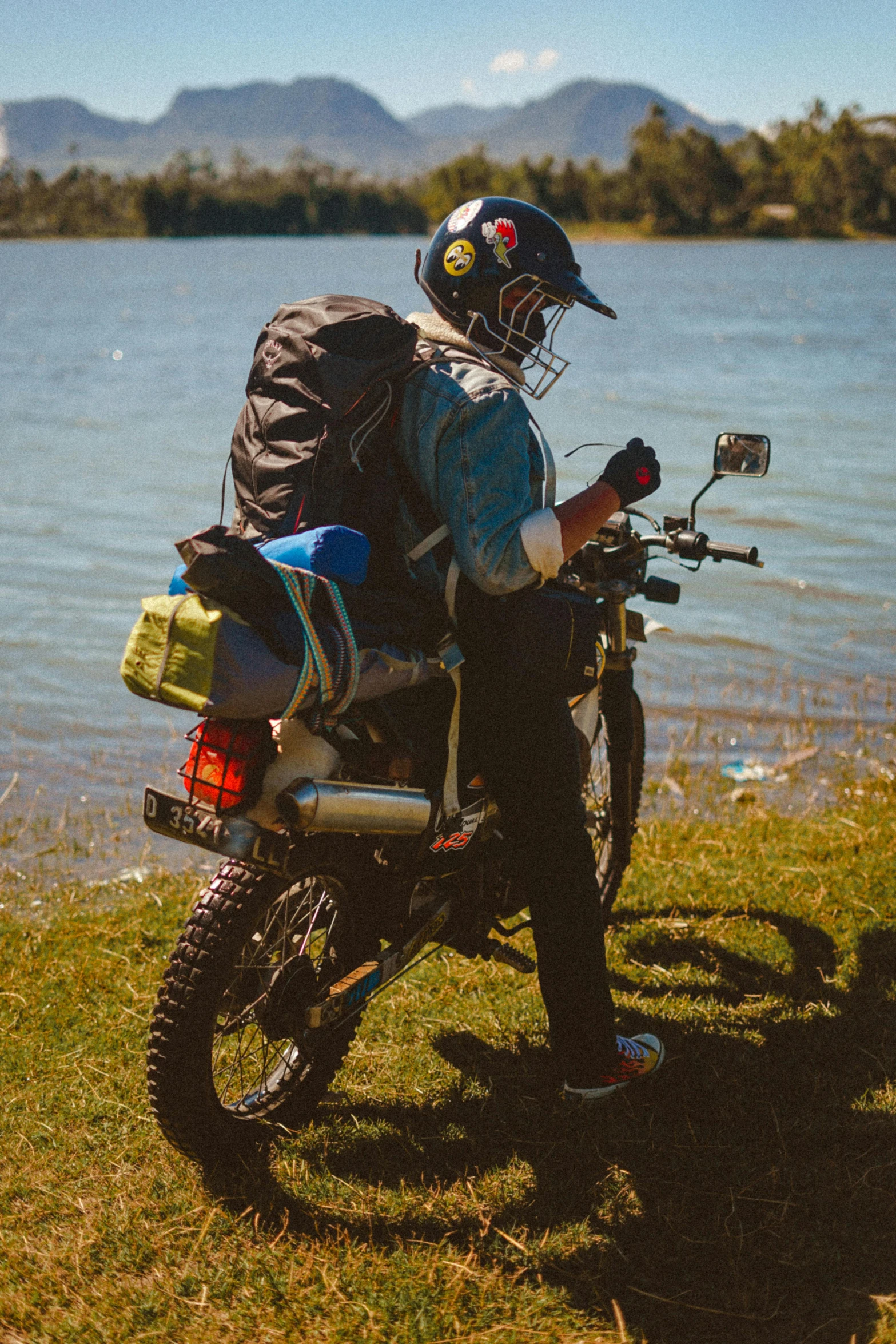 a man in motorcycle gear sitting on a bike near the water