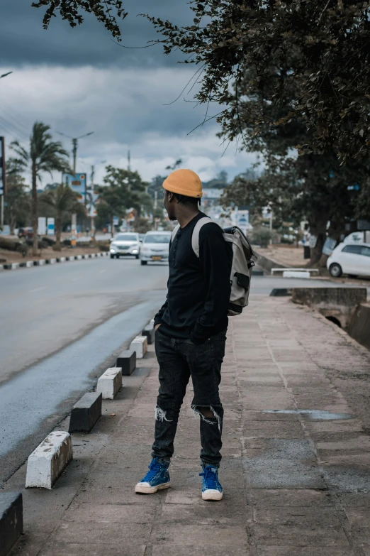 a man with a backpack standing next to a road