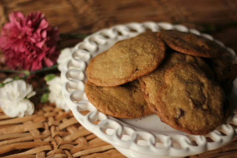 cookies are stacked up on a plate beside a pink flower