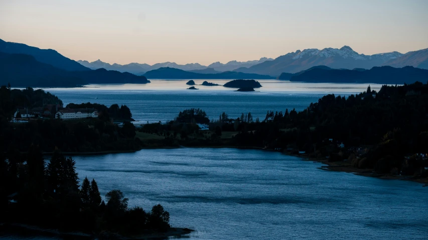 a body of water surrounded by mountains at dusk