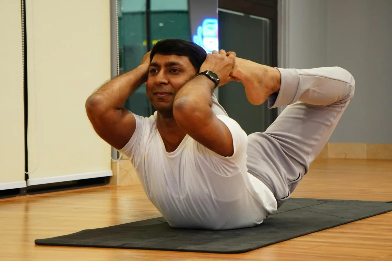 an indian man doing the splits while lying on a mat