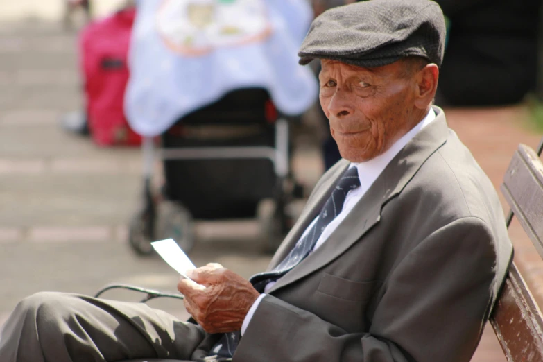 an elderly man is sitting on a bench outside