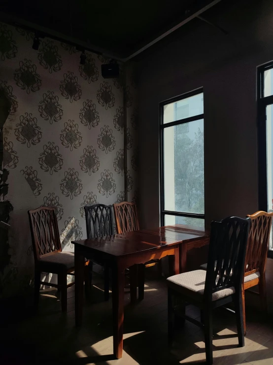 a large wooden table sitting under two windows