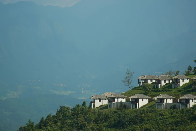 several white houses sitting on top of a grassy hill