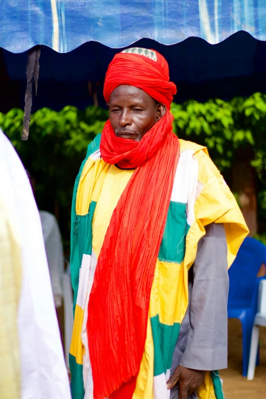 man in brightly colored scarf standing outside under an umbrella