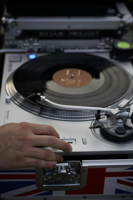 man's hand pressing record into turntable on united kingdom flag