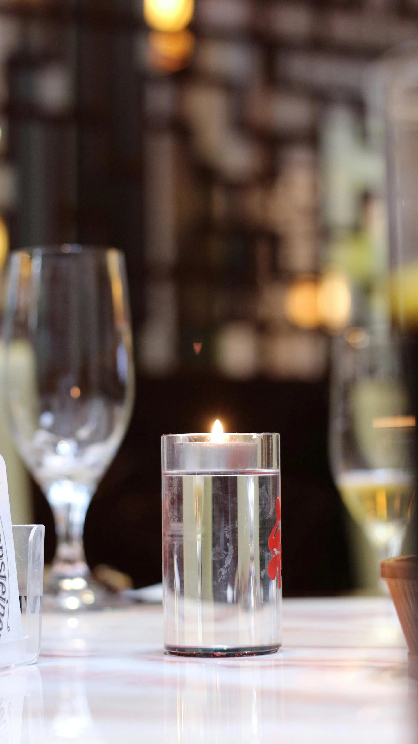 the table has two glasses, an empty wine glass and a candle