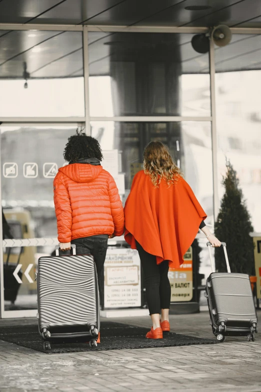 two people with suitcases walking through the airport