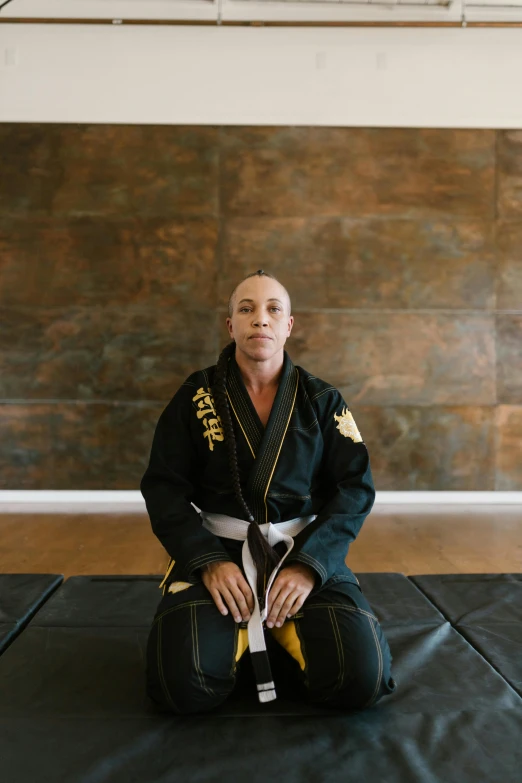 a woman sitting on top of a mat with a black karate outfit