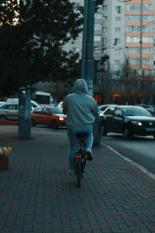 a man riding on the back of a bike down a sidewalk