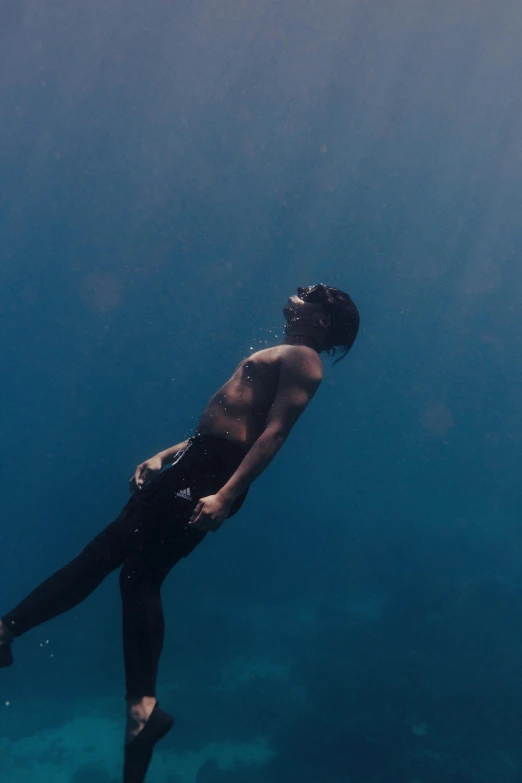 man wearing diving gear in the ocean with his back to us