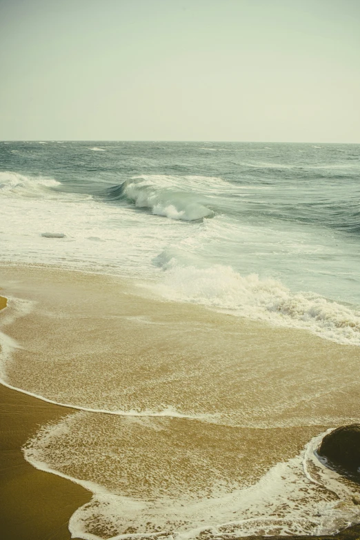 a person is walking along the beach as waves come in