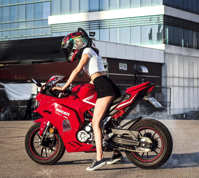 a woman on a motorcycle with a helmet is posing for the camera