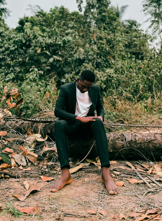 a man in a suit sitting on a fallen tree