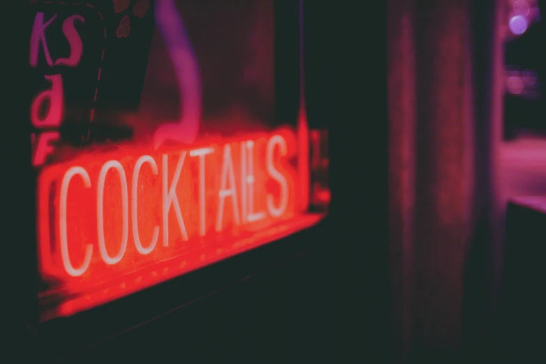 a neon sign advertising cocktails is shown in a window