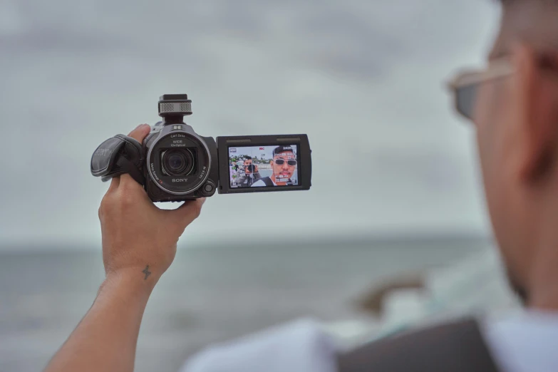 man taking po in front of the ocean with his camera