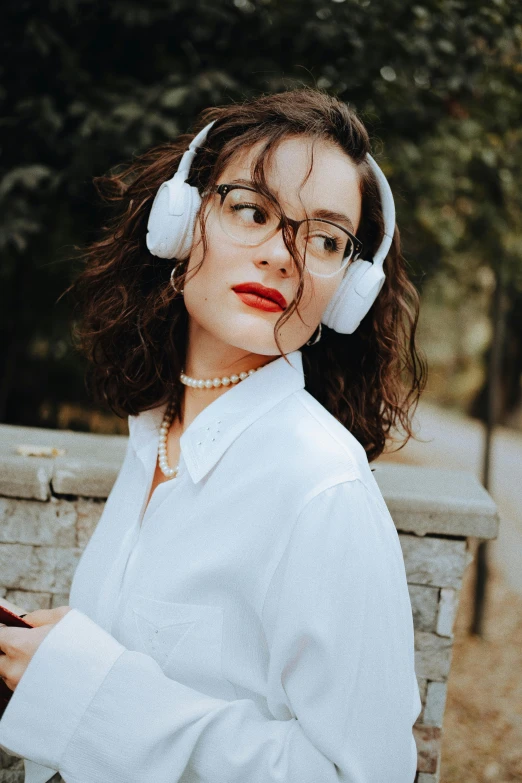 the girl is holding her cell phone while wearing headphones