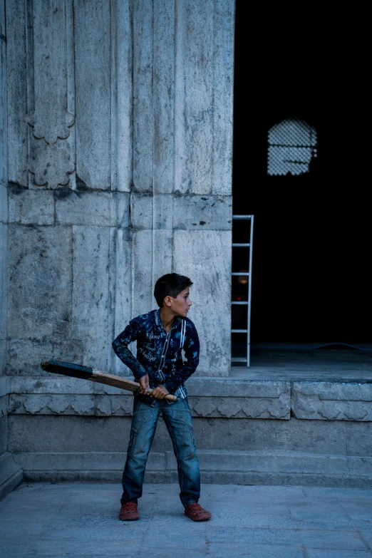 a boy is holding a baseball bat by a building